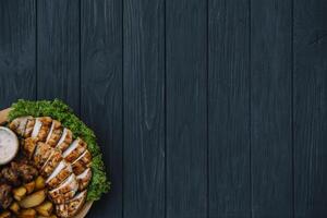 Most meat dish - beef kebabs, sausages, grilled mushrooms, potatoes, tomatoes and sauce. The best choice for a beer. Close-up on a wooden background. photo