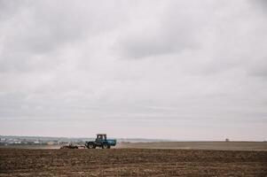 Farmer in tractor preparing land with seedbed cultivator in farmlands. photo