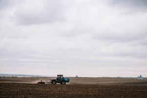 Farmer in tractor preparing land with seedbed cultivator in farmlands. photo