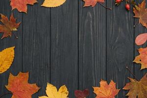 Background texture with old wooden table and yellow autumnal leaves. Autumn maple leaves on wooden background with copy space. Top view. photo