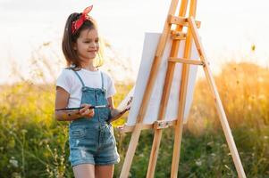 education, school, art and painitng concept - little student girl painting picture. photo