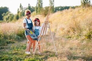 Young mother and her daughter have fun, mother's Day. smiling mother with beautiful daughter draws nature. photo