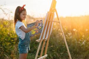 Little Girl Is Painting Picture Outdoors. photo