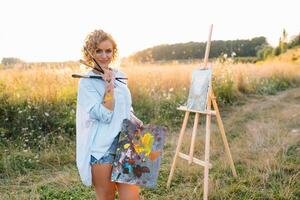 Talented artist in outdoors is mixing paint for her new project while holding brushes photo