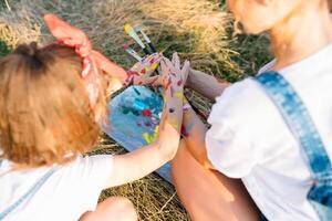 Sunny nature, mom and daughter paint a picture in a park , painting a Little Child, Child Creativity. Mother's Day. photo