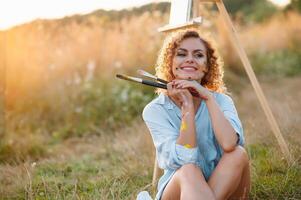 Pretty woman is painting. Open air session. Cute woman draws a picture at sunset. girl artist. photo