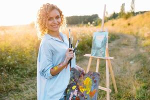 Pretty woman is painting. Open air session. Cute woman draws a picture at sunset. girl artist. photo