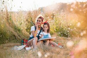 Young mother and her daughter have fun, mother's Day. smiling mother with beautiful daughter draws nature. photo