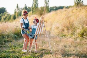 Young mother and her daughter have fun, mother's Day. smiling mother with beautiful daughter draws nature. photo