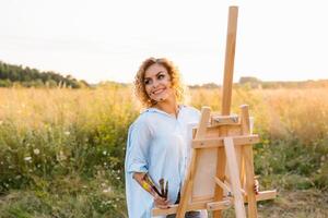 Pretty talented female painter painting on easel, making colorful sketches, creating marine landscape. Beautiful female artist painting with watercolor paints. Creativity and imagination concept photo