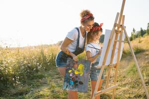 Young mother and her daughter have fun, mother's Day. smiling mother with beautiful daughter draws nature. photo