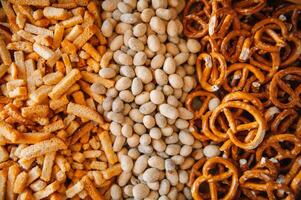 Mix of snacks pretzels , crackers , chips , nuts and nachos. Lager beer and snacks on stone table. Nuts, chips, pretzel. Top view with copy space. photo