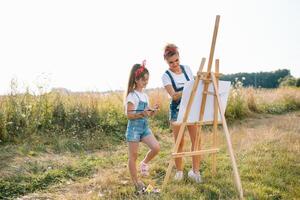 Young mother and her daughter have fun, mother's Day. smiling mother with beautiful daughter draws nature photo