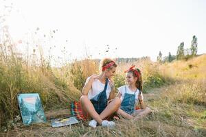 Young mother and her daughter have fun, mother's Day. smiling mother with beautiful daughter draws nature. photo