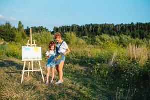 Young mother and her daughter have fun, mother's Day. smiling mother with beautiful daughter draws nature. photo