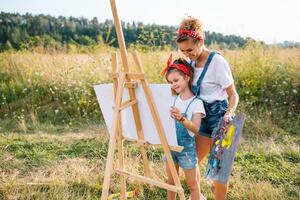 Young mother and her daughter have fun, mother's Day. smiling mother with beautiful daughter draws nature. photo