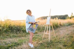 Talented artist in outdoors is mixing paint for her new project while holding brushes photo