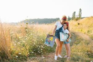 belleza madre pintar con su pequeño hija. elegante mujer dibujo el imagen con pequeño muchacha. linda niño en un blanco camiseta y azul vaqueros. de la madre día. foto