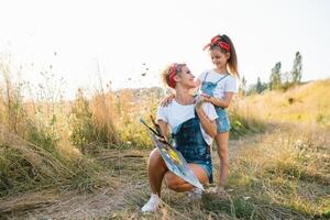 Young mother and her daughter have fun, mother's Day. smiling mother with beautiful daughter draws nature. photo