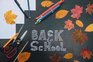 Back to school concept. School and office supplies on blackboard background photo