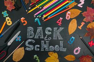 Back to school concept. School and office supplies on blackboard background photo