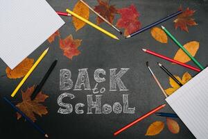 Back to school concept. School and office supplies on blackboard background photo