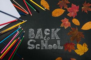 Back to school concept. School and office supplies on blackboard background photo