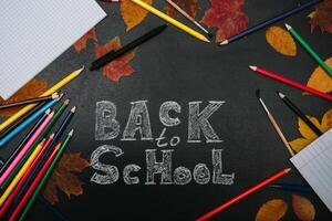 Back to school concept. School and office supplies on blackboard background photo