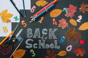 Back to school concept. School and office supplies on blackboard background photo