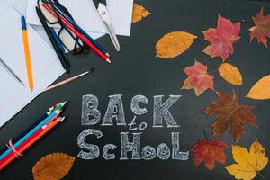 Back to school concept. School and office supplies on blackboard background photo