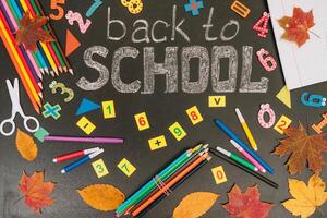 Back to school concept. School and office supplies on blackboard background photo