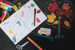 Back to school concept. School and office supplies on blackboard background photo