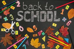 Back to school concept. School and office supplies on blackboard background photo