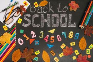 Back to school concept. School and office supplies on blackboard background photo