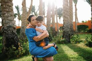 Stylish mother and handsome son having fun on a green lawn. Happy family concept. Beauty nature scene with family outdoor lifestyle. Happy family resting together. Mothers day photo