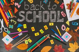 Back to school concept. School and office supplies on blackboard background photo