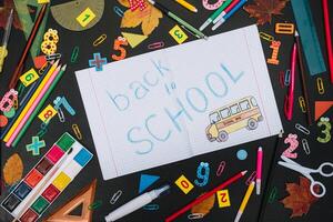 Back to school concept. School and office supplies on blackboard background photo