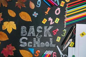 Back to school concept. School and office supplies on blackboard background photo