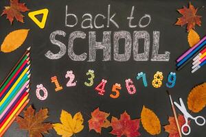 Back to school concept. School and office supplies on blackboard background photo