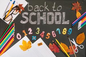 Back to school concept. School and office supplies on blackboard background photo