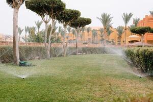 Modern device of irrigation garden. Irrigation system - technique of watering in the garden. Lawn sprinkler spraying water over green grass. photo