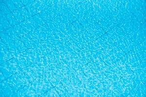 Water ripples on blue tiled swimming pool background. View from above. photo