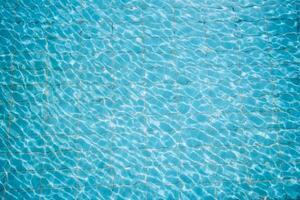 Water ripples on blue tiled swimming pool background. View from above. photo