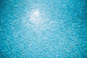 Water ripples on blue tiled swimming pool background. View from above. photo