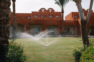 Modern device of irrigation garden. Irrigation system - technique of watering in the garden. Lawn sprinkler spraying water over green grass. photo