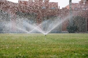 Modern device of irrigation garden. Irrigation system - technique of watering in the garden. Lawn sprinkler spraying water over green grass. photo