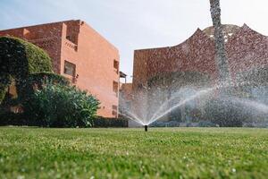 Modern device of irrigation garden. Irrigation system - technique of watering in the garden. Lawn sprinkler spraying water over green grass. photo