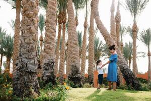 Stylish mother and handsome son having fun on a green lawn. Happy family concept. Beauty nature scene with family outdoor lifestyle. Happy family resting together. Mothers day photo