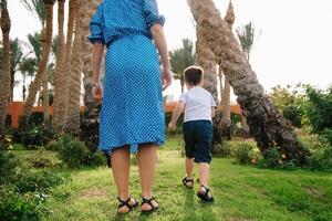 Stylish mother and handsome son having fun on a green lawn. Happy family concept. Beauty nature scene with family outdoor lifestyle. Happy family resting together. Mothers day photo