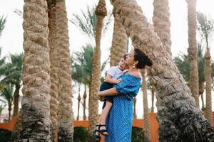 Stylish mother and handsome son having fun on a green lawn. Happy family concept. Beauty nature scene with family outdoor lifestyle. Happy family resting together. Mothers day photo